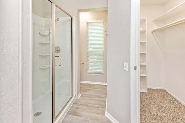 114 Juniper Dr, Arlington, TX 76018 - full bath featuring a stall shower, a walk in closet, a textured wall, baseboards, and wood finished floors