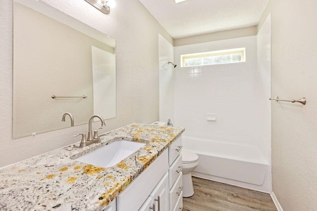 114 Juniper Dr, Arlington, TX 76018 - bathroom featuring wood finished floors, vanity, toilet, bathing tub / shower combination, and a textured wall