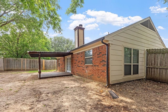 114 Juniper Dr, Arlington, TX 76018 - view of side of home featuring brick siding, a fenced backyard, a chimney, a patio, and french doors
