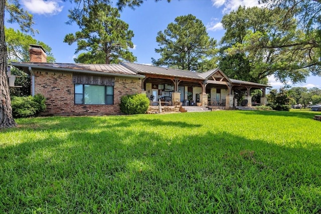 6903 Scott St, Eustace, TX 75124 - rear view of house with a lawn, brick siding, a chimney, metal roof, and a standing seam roof