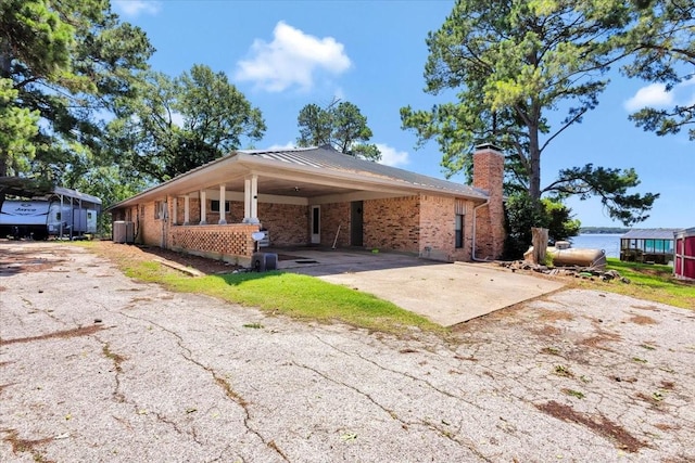 6903 Scott St, Eustace, TX 75124 - view of front of home with asphalt driveway, brick siding, a chimney, a carport, and a water view