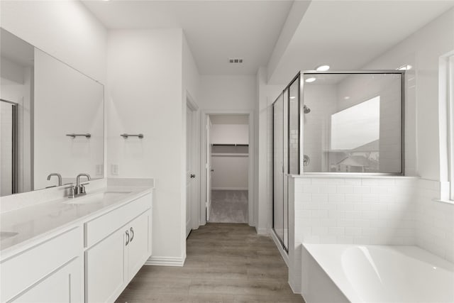 713 Roanoke, Princeton, TX 75407 - bathroom with a stall shower, double vanity, a garden tub, a spacious closet, and wood finished floors