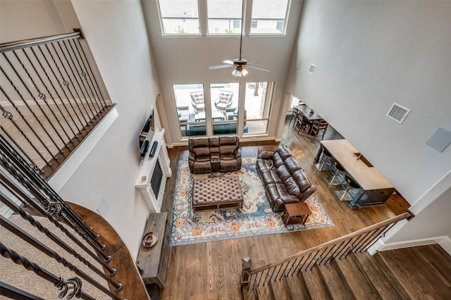 15186 Crape Myrtle Rd, Frisco, TX 75035 - living area featuring wood finished floors, stairway, ceiling fan, a towering ceiling, and a fireplace