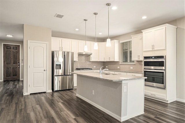 2535 Candle Ln, Northlake, TX 76247 - kitchen featuring appliances with stainless steel finishes, under cabinet range hood, dark wood finished floors, decorative backsplash, and recessed lighting