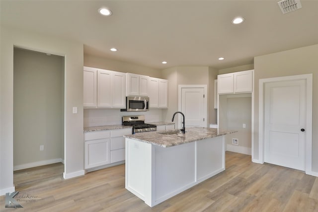 3458 Pewter Ln, Abilene, TX 79601 - kitchen featuring appliances with stainless steel finishes, a sink, white cabinets, light stone counters, and light wood-style flooring