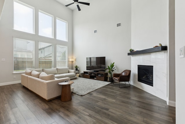 12469 Diamond Creek Dr, Frisco, TX 75035 - living area featuring a towering ceiling, ceiling fan, dark wood-style flooring, a tiled fireplace, and baseboards