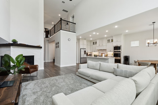 12469 Diamond Creek Dr, Frisco, TX 75035 - living room featuring dark wood-style floors, a chandelier, recessed lighting, a premium fireplace, and baseboards