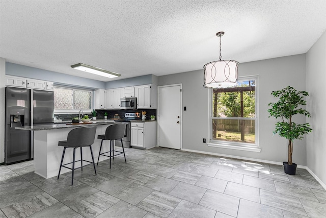 4910 Crest Dr, Arlington, TX 76017 - kitchen with appliances with stainless steel finishes, dark countertops, a textured ceiling, baseboards, and backsplash