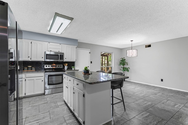 4910 Crest Dr, Arlington, TX 76017 - kitchen featuring stainless steel appliances, a kitchen island, a breakfast bar, white cabinetry, and decorative backsplash