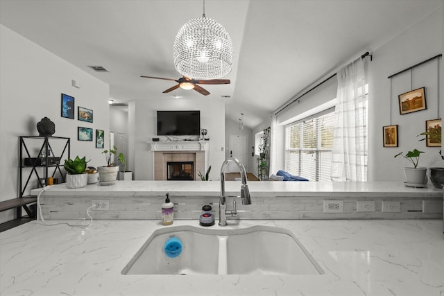 1521 Cherokee Rose Trl, Savannah, TX 76227 - kitchen with a sink, light stone counters, a tiled fireplace, and a ceiling fan