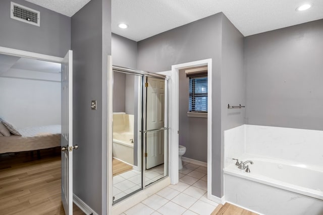 213 County Road 1407, Jacksonville, TX 75766 - ensuite bathroom with a garden tub, toilet, a stall shower, baseboards, and a textured ceiling