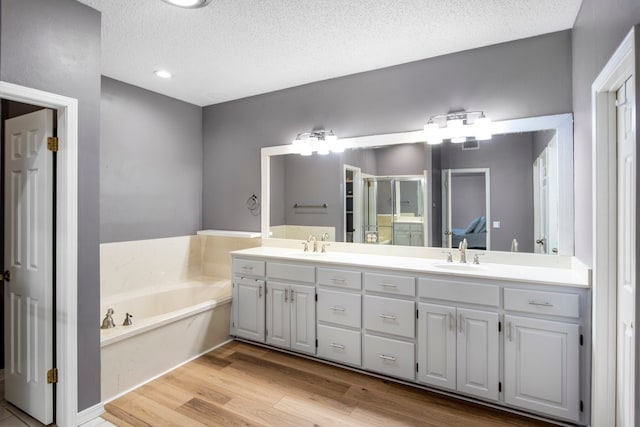 213 County Road 1407, Jacksonville, TX 75766 - full bath with double vanity, a stall shower, a bath, wood finished floors, and a textured ceiling