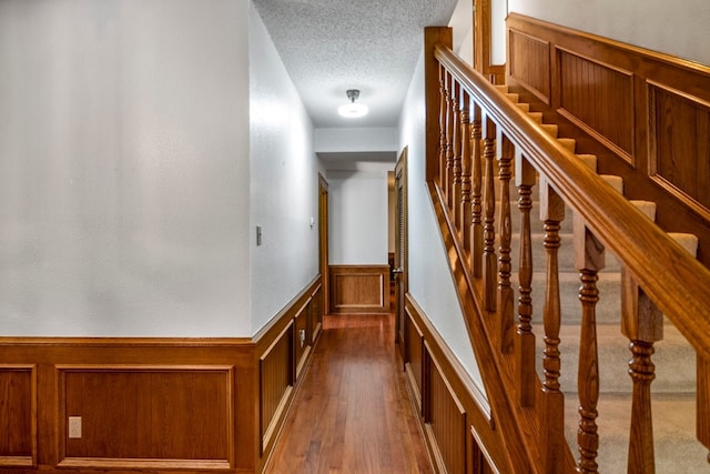 213 County Road 1407, Jacksonville, TX 75766 - stairway with wainscoting, a decorative wall, a textured ceiling, and wood finished floors