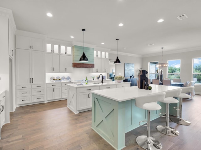 213 Martin Dr, Granbury, TX 76049 - kitchen featuring an island with sink, crown molding, wood finished floors, glass insert cabinets, and recessed lighting