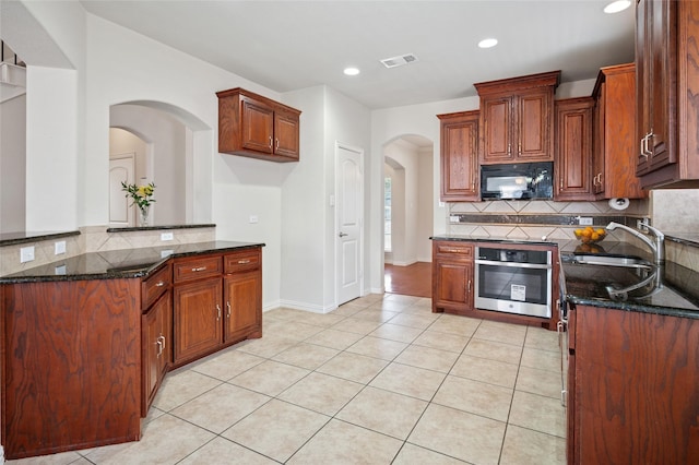 9004 Mcfarland Way, Fort Worth, TX 76244 - kitchen with oven, black microwave, a sink, arched walkways, and tasteful backsplash