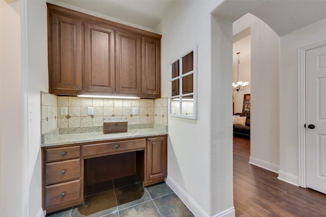 1036 Knoxbridge Rd, Forney, TX 75126 - kitchen with a chandelier, tasteful backsplash, brown cabinets, light stone counters, and dark wood-type flooring