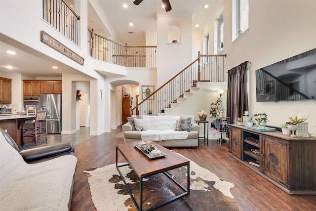 1036 Knoxbridge Rd, Forney, TX 75126 - living room featuring ceiling fan, stairway, arched walkways, a towering ceiling, and dark wood-style floors