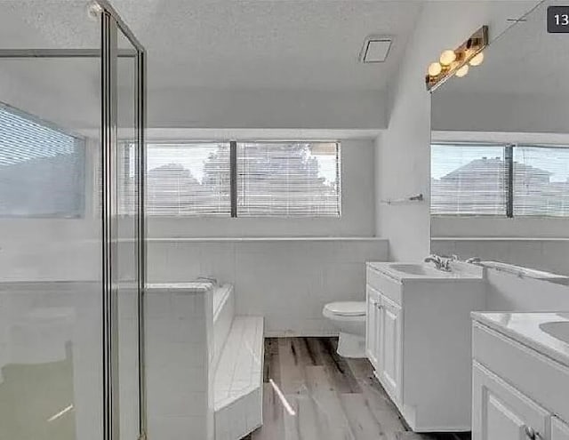1737 Liberty Ln, Mesquite, TX 75149 - bathroom with two vanities, toilet, wood finished floors, a stall shower, and a textured ceiling