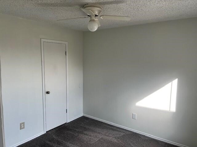 1737 Liberty Ln, Mesquite, TX 75149 - empty room with a ceiling fan, dark colored carpet, and a textured ceiling