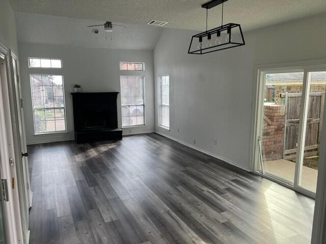 1737 Liberty Ln, Mesquite, TX 75149 - unfurnished living room featuring dark wood-style flooring, a textured ceiling, lofted ceiling, and baseboards