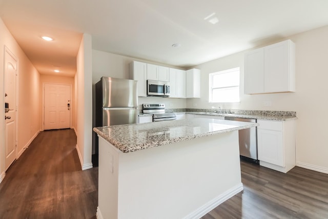 471 Bobbie St, Mabank, TX 75147 - kitchen with appliances with stainless steel finishes, dark wood-type flooring, white cabinets, a kitchen island, and light stone counters