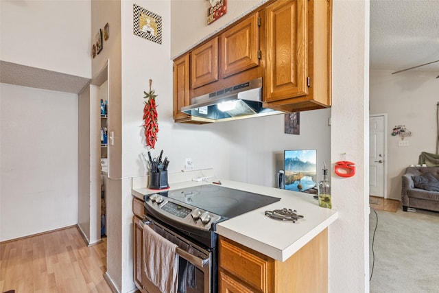 1005 Blue Jay Dr, Mansfield, TX 76063 - kitchen with electric stove, under cabinet range hood, light countertops, brown cabinets, and a textured ceiling