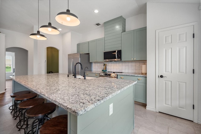 800 Bur Oak Dr, Burleson, TX 76028 - kitchen featuring arched walkways, appliances with stainless steel finishes, tasteful backsplash, a kitchen breakfast bar, and light stone counters