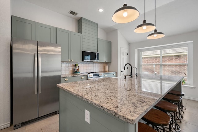 800 Bur Oak Dr, Burleson, TX 76028 - kitchen with stainless steel appliances, backsplash, light tile patterned floors, light stone counters, and a kitchen island with sink
