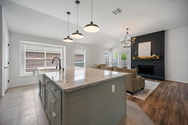800 Bur Oak Dr, Burleson, TX 76028 - kitchen with gray cabinets, baseboards, a kitchen island with sink, light stone countertops, and lofted ceiling