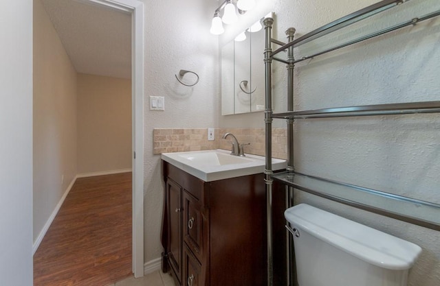 4501 Mink Dr, Haltom City, TX 76117 - half bath featuring vanity, tasteful backsplash, toilet, a textured wall, and wood finished floors