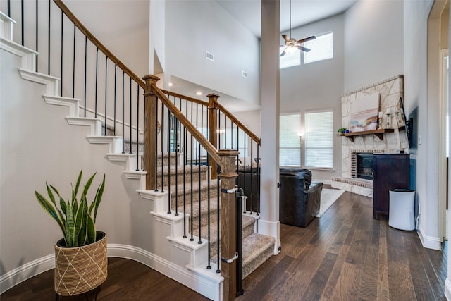 1225 Horsemint Dr, Little Elm, TX 75068 - stairway featuring wood finished floors, a ceiling fan, a towering ceiling, a fireplace, and baseboards
