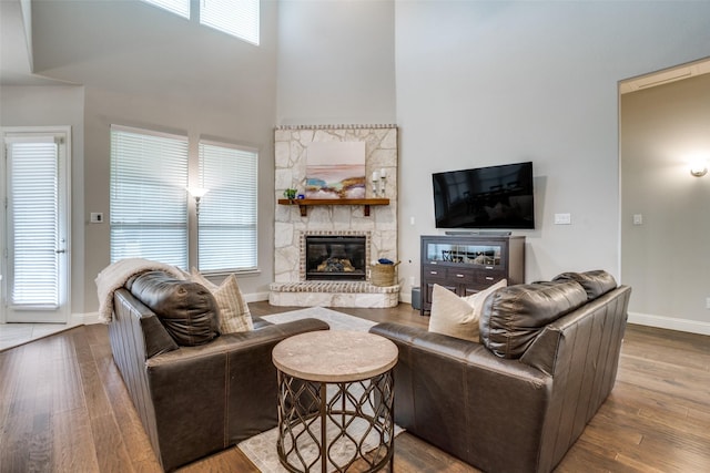 1225 Horsemint Dr, Little Elm, TX 75068 - living room featuring a fireplace, wood finished floors, a towering ceiling, and baseboards