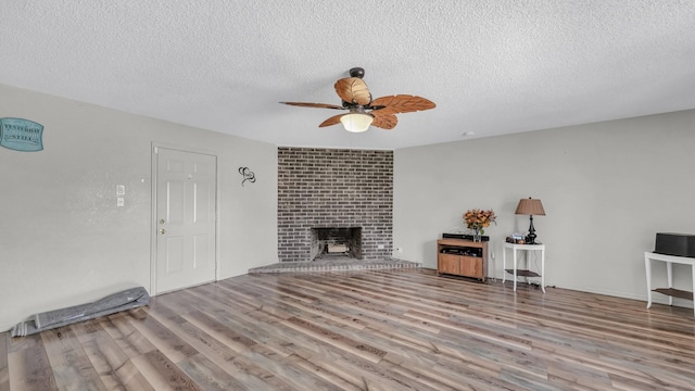 239 N 10th St, Jacksboro, TX 76458 - living room featuring ceiling fan, a textured ceiling, wood finished floors, and a fireplace