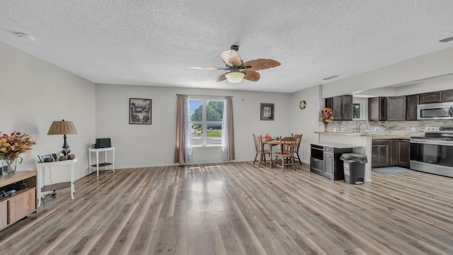 239 N 10th St, Jacksboro, TX 76458 - kitchen featuring appliances with stainless steel finishes, light countertops, light wood-style flooring, a textured ceiling, and tasteful backsplash