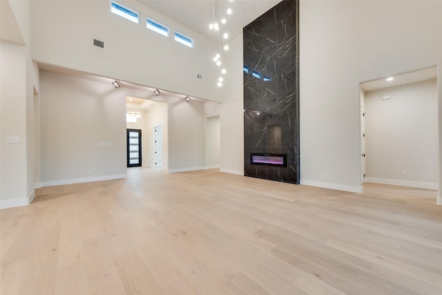 1700 Hamilton Ln, Northlake, TX 76247 - unfurnished living room with a high ceiling, a high end fireplace, light wood-style flooring, and baseboards