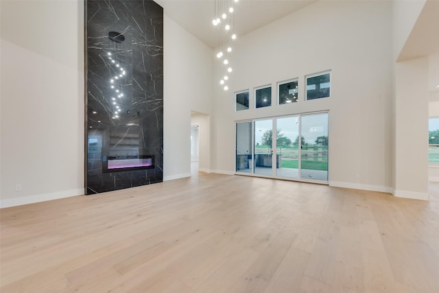 1700 Hamilton Ln, Northlake, TX 76247 - unfurnished living room featuring a towering ceiling, baseboards, a fireplace, and wood finished floors