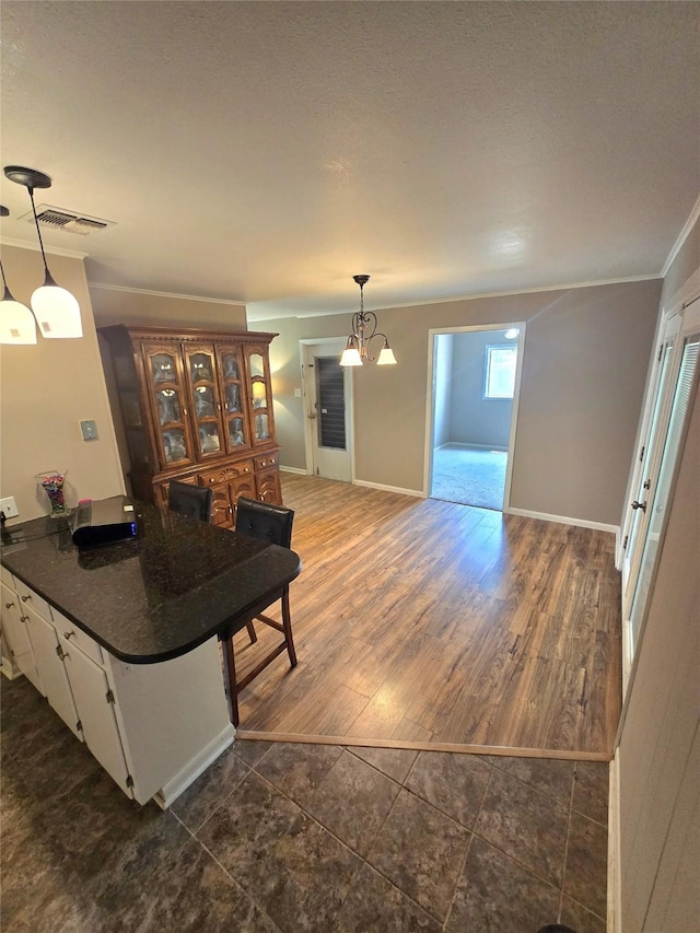 9474 Poinsetta Dr, Shreveport, LA 71118 - kitchen featuring dark countertops, white cabinets, ornamental molding, hanging light fixtures, and dark tile patterned floors