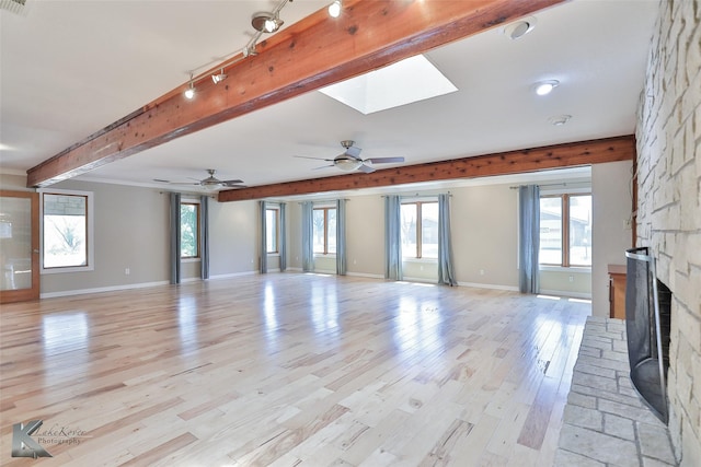 920 SW 3rd St, Hamlin, TX 79520 - unfurnished living room with a fireplace, beam ceiling, track lighting, light wood-style flooring, and baseboards