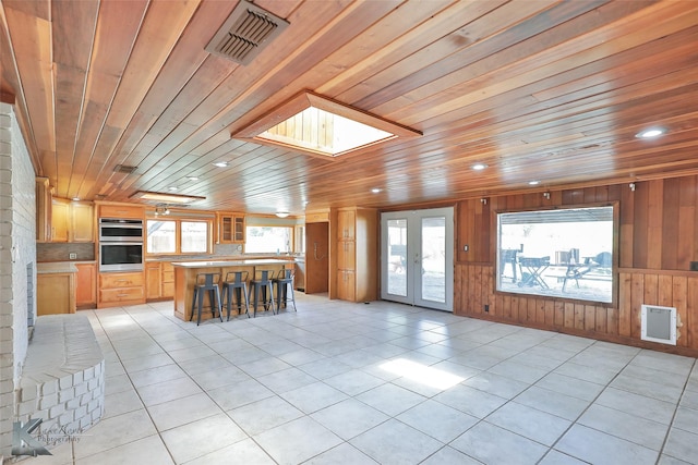 920 SW 3rd St, Hamlin, TX 79520 - kitchen featuring double oven, wood ceiling, light countertops, light tile patterned floors, and a kitchen bar