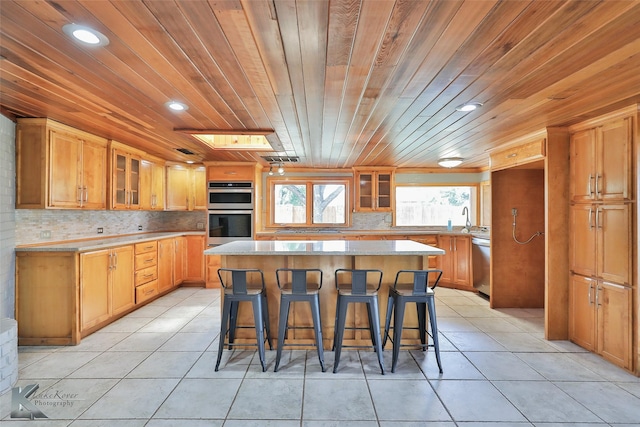 920 SW 3rd St, Hamlin, TX 79520 - kitchen with stainless steel appliances, a kitchen bar, light tile patterned floors, a kitchen island, and wood ceiling