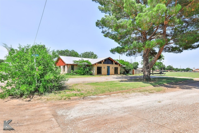 920 SW 3rd St, Hamlin, TX 79520 - view of front of house with dirt driveway, stone siding, and metal roof