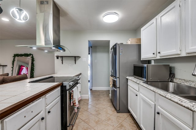 3232 Bunker Hill Dr, Forest Hill, TX 76140 - kitchen with appliances with stainless steel finishes, wall chimney range hood, white cabinets, a sink, and light tile patterned floors