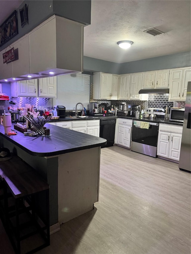 1213 Southridge Dr, Lancaster, TX 75146 - kitchen featuring stainless steel appliances, dark countertops, under cabinet range hood, tasteful backsplash, and a textured ceiling