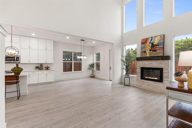 5634 Barkridge Dr, Granbury, TX 76048 - living room with a chandelier, a stone fireplace, a towering ceiling, recessed lighting, and light wood finished floors