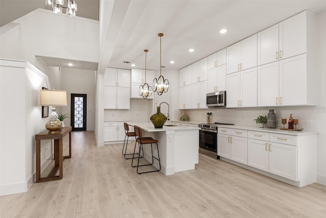 5634 Barkridge Dr, Granbury, TX 76048 - kitchen featuring appliances with stainless steel finishes, decorative backsplash, light wood-style flooring, recessed lighting, and an island with sink