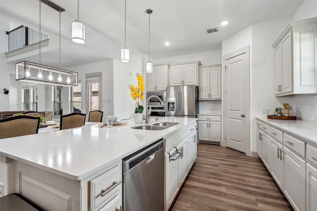 12947 Cabana Dr, Frisco, TX 75035 - kitchen with stainless steel appliances, recessed lighting, tasteful backsplash, dark wood-type flooring, and a kitchen island with sink