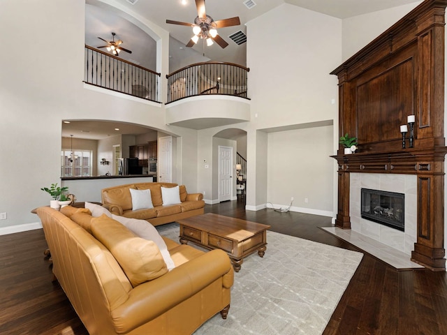 1025 Arches Park Dr, Allen, TX 75013 - living room with a ceiling fan, wood finished floors, baseboards, a fireplace, and a towering ceiling