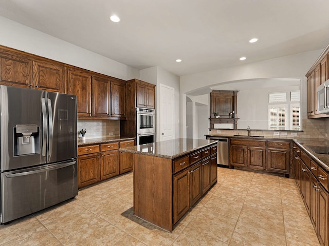 1025 Arches Park Dr, Allen, TX 75013 - kitchen with stainless steel appliances, a sink, arched walkways, decorative backsplash, and recessed lighting