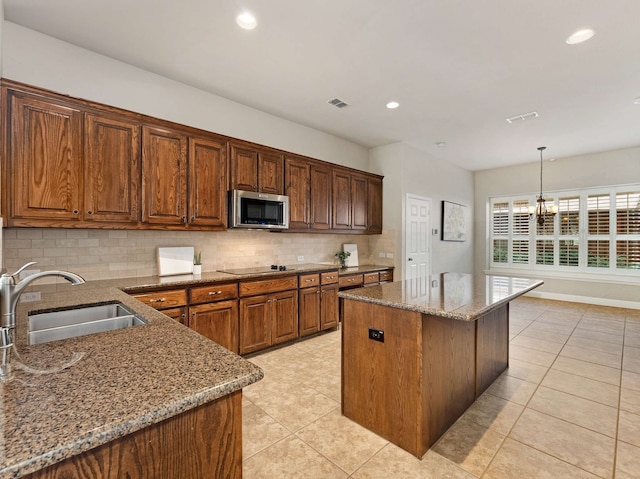 1025 Arches Park Dr, Allen, TX 75013 - kitchen with stainless steel microwave, a sink, stone counters, tasteful backsplash, and light tile patterned floors