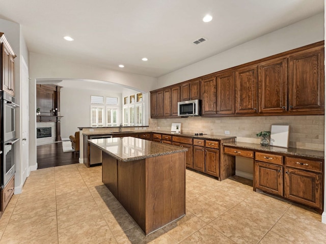 1025 Arches Park Dr, Allen, TX 75013 - kitchen with stainless steel appliances, arched walkways, tasteful backsplash, dark stone counters, and a sink